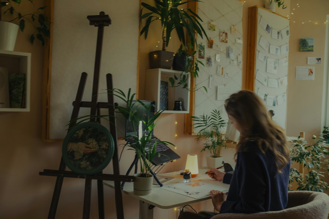 Une jeune femme dessine à son bureau, dans une pièce chaleureuse